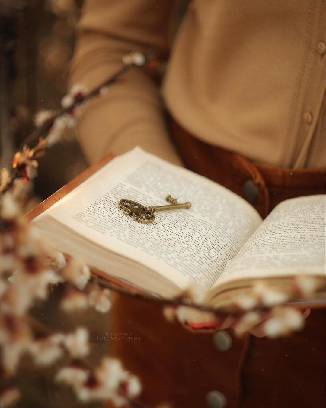 Livro aberto com uma chave antiga sobre as páginas, cercado por flores